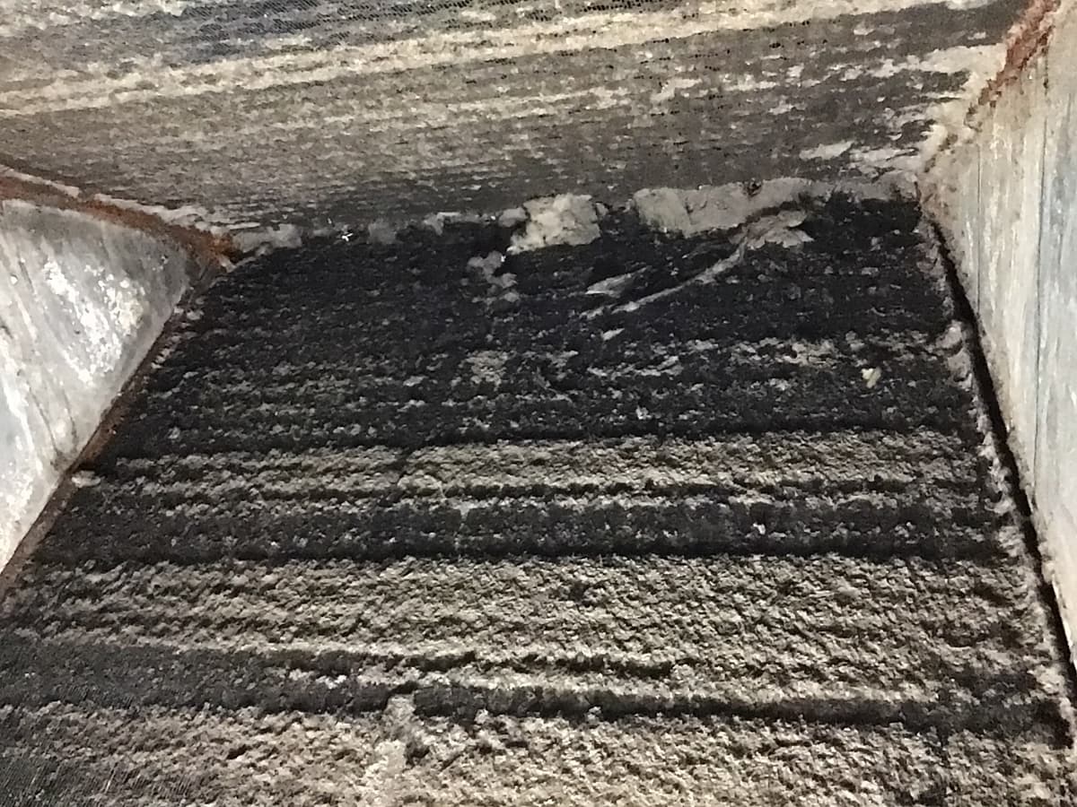 An evaporator coil with dust caked across the fins before cleaning