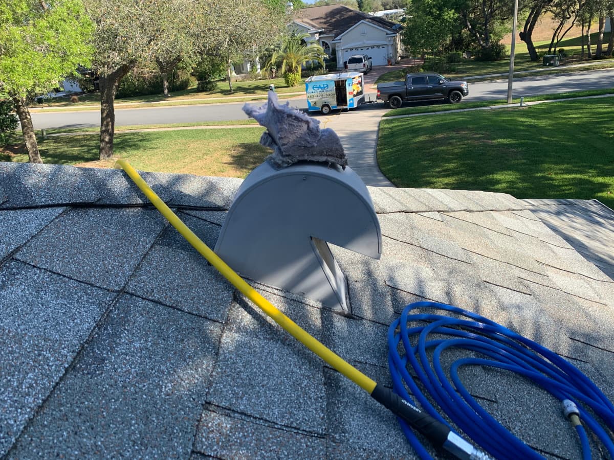 A cleaning line fed into a roof dryer vent cap above a residential street