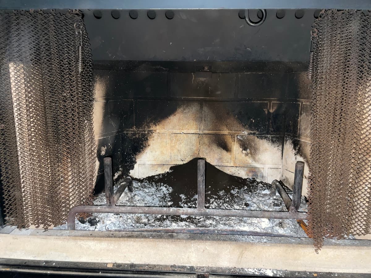 A fireplace with soot and creosote on the firebox walls during chimney cleaning