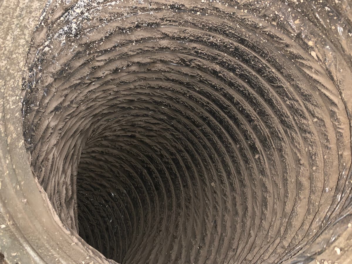 A flexible duct coated in brown dust before cleaning
