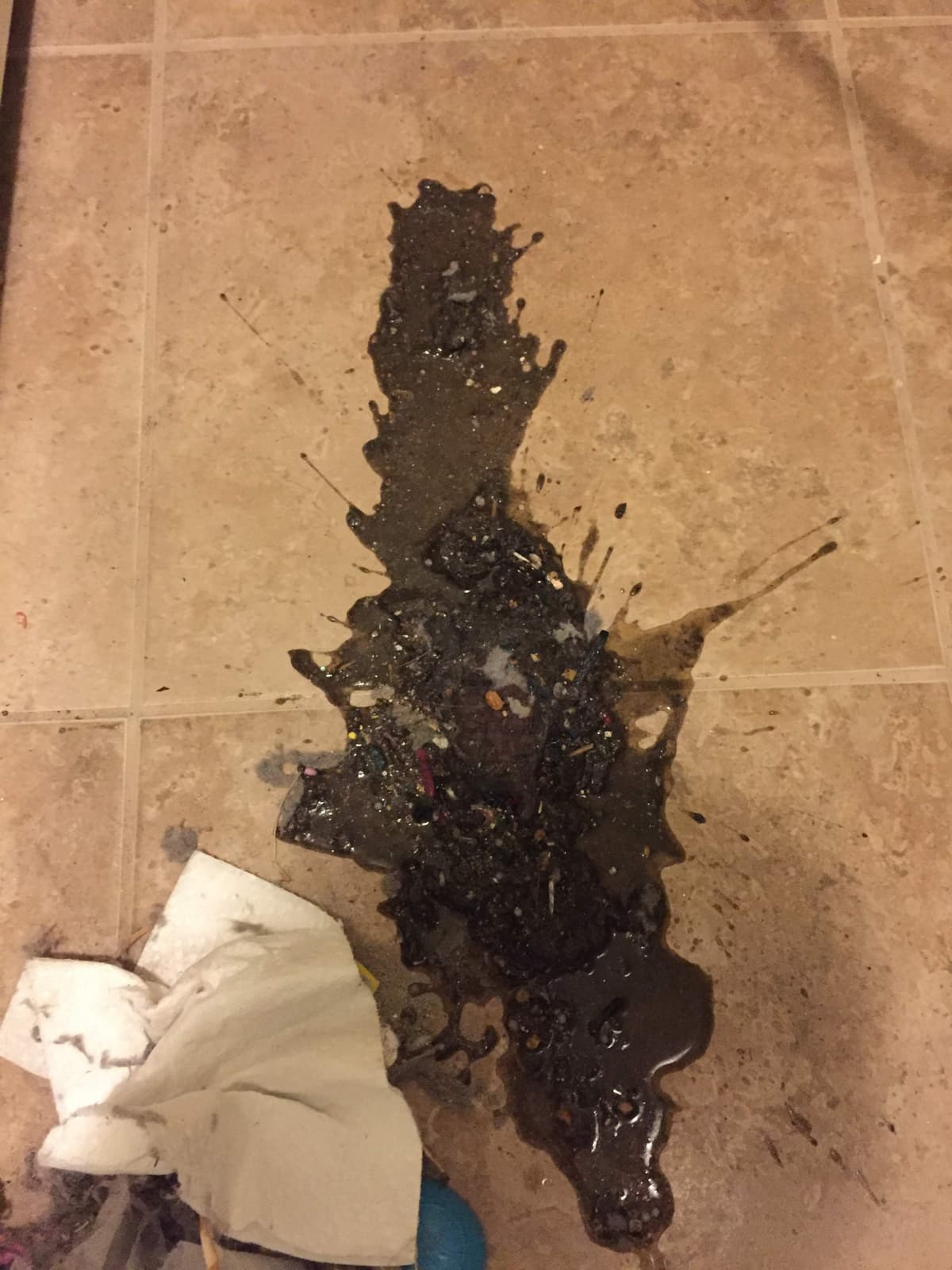 Water and wet lint spilled onto a tile floor from a clogged dryer vent connection