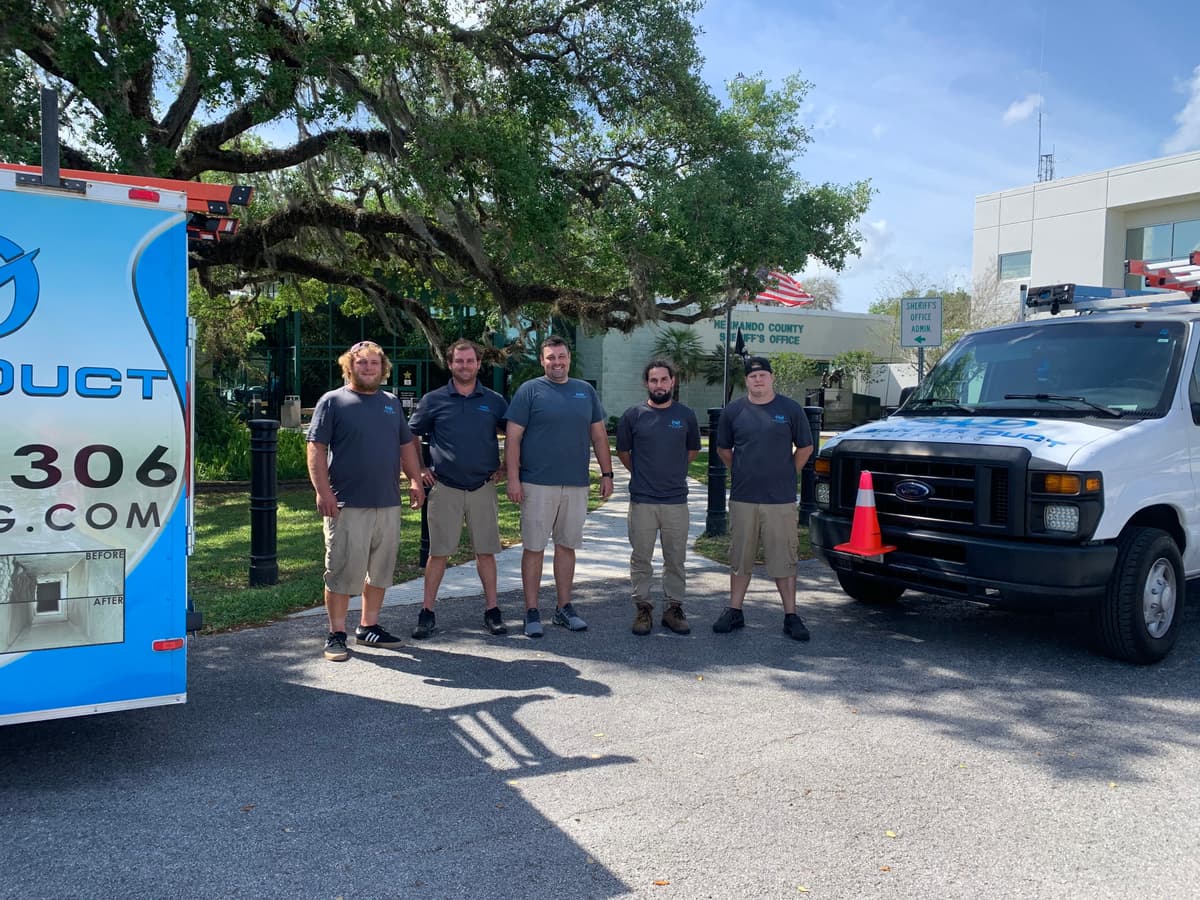 The Clean Air Duct Cleaning crew standing beside their work van after a commercial duct cleaning job