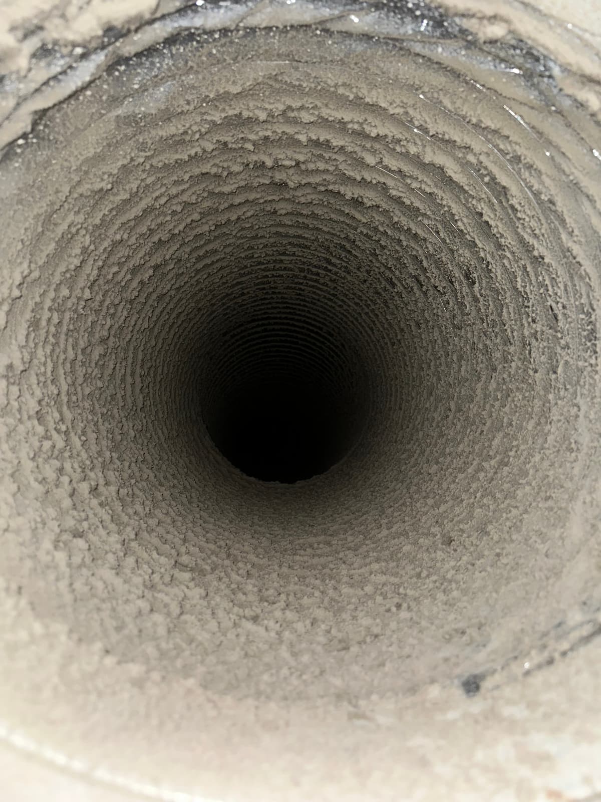 A return trunk at the air handler before cleaning, lined with matted dust