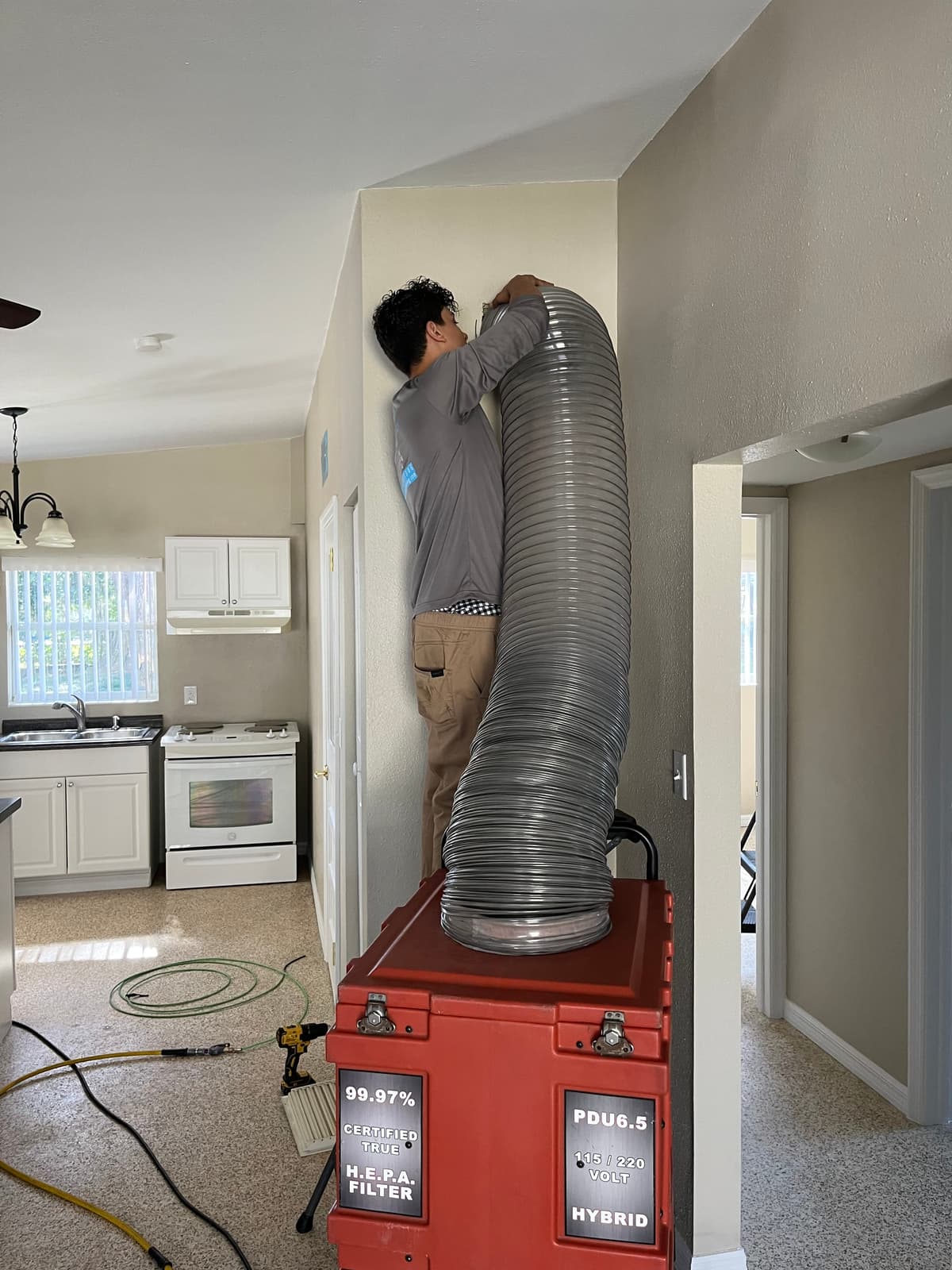 A Clean Air Duct Cleaning technician connecting a negative air machine hose to a home's HVAC system
