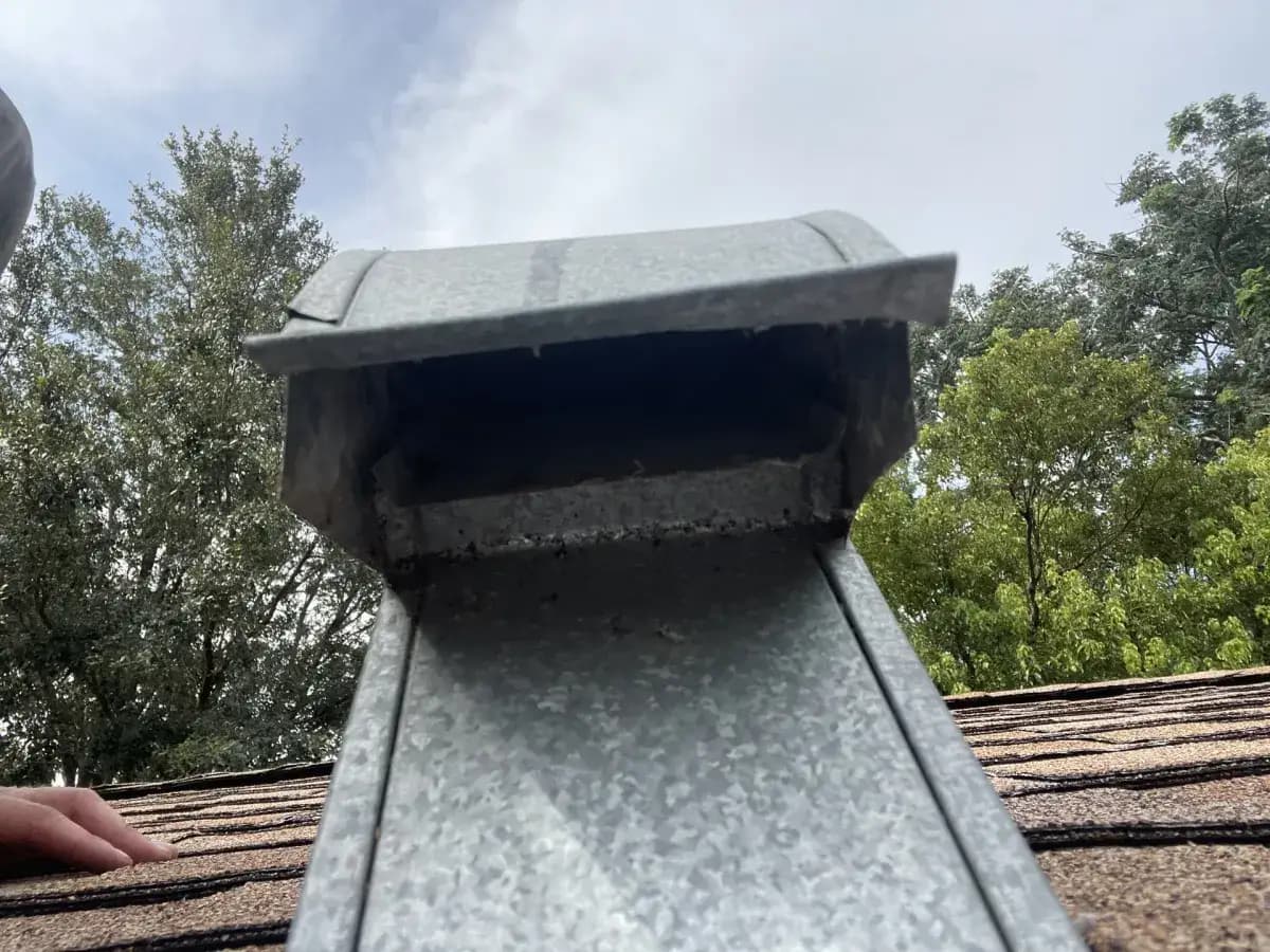 A metal chimney chase cover on a shingle roof