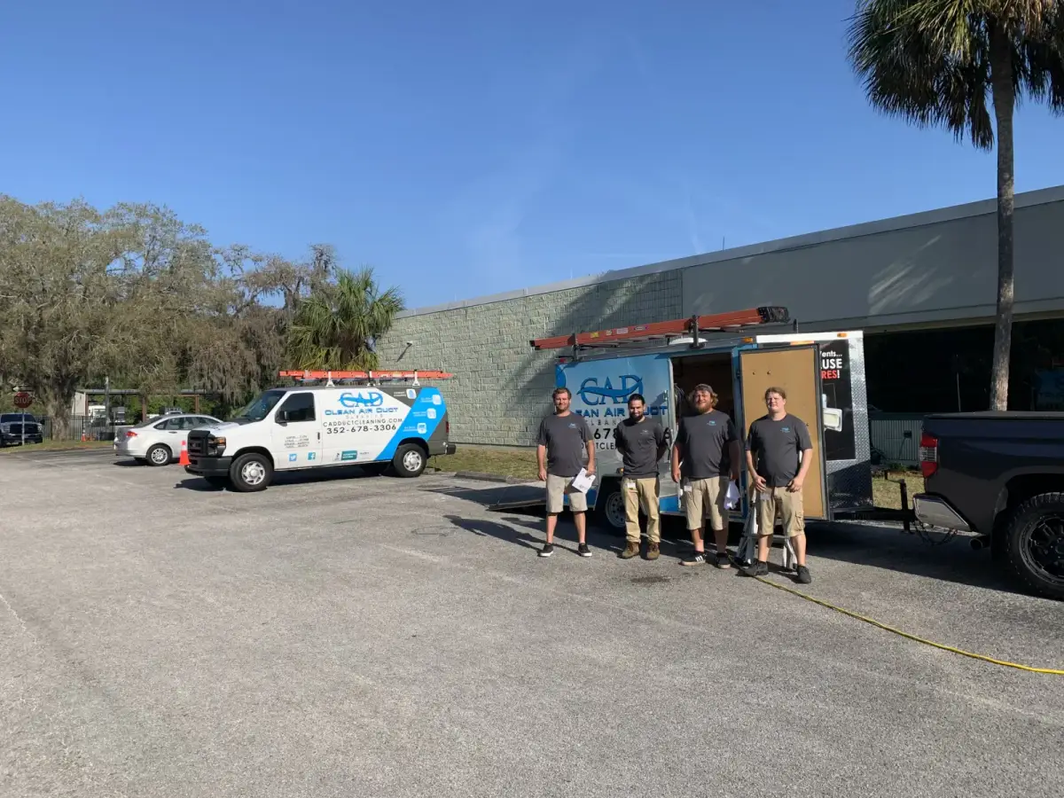 The Clean Air Duct Cleaning crew standing with their vans before a commercial job