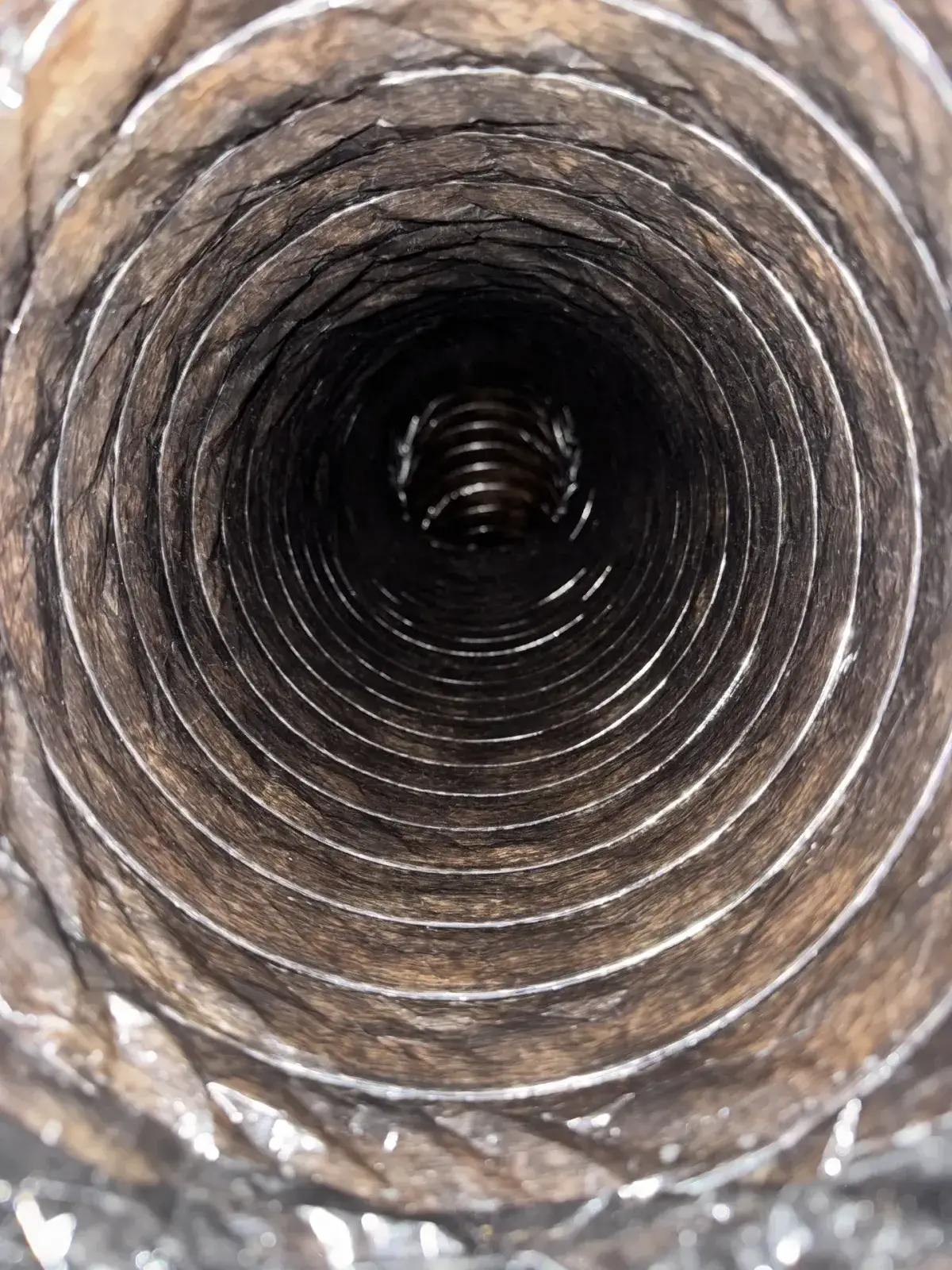 A brown, dust-coated duct before cleaning