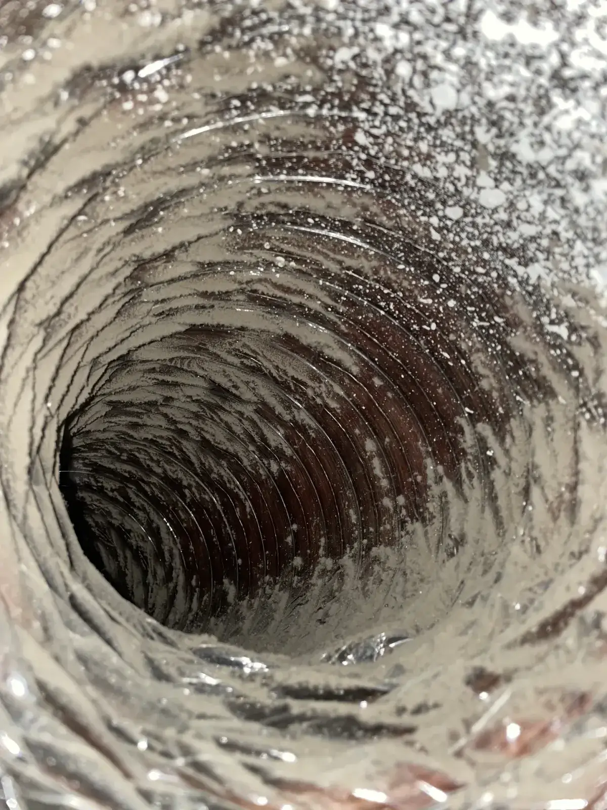 A dust-coated flexible duct interior before cleaning