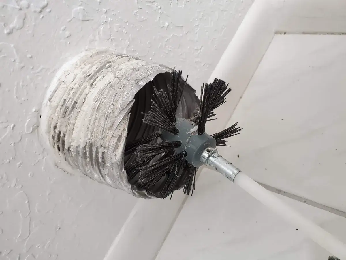 A rotary brush working inside a dryer vent wall opening
