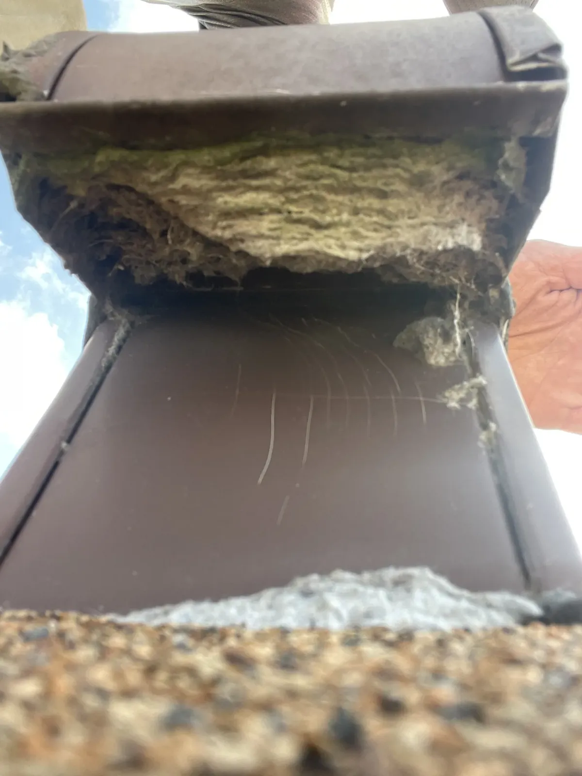 A roof dryer vent hood held open, its throat packed solid with matted lint
