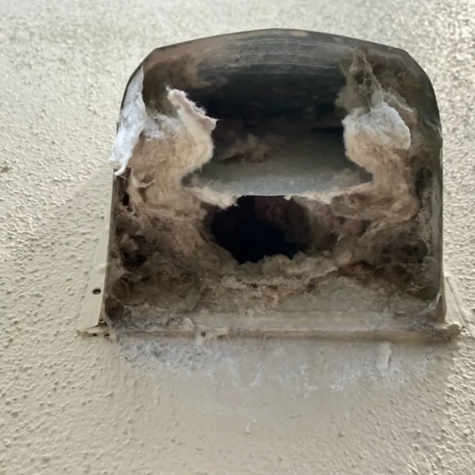 A wall dryer vent hood packed with lint before cleaning