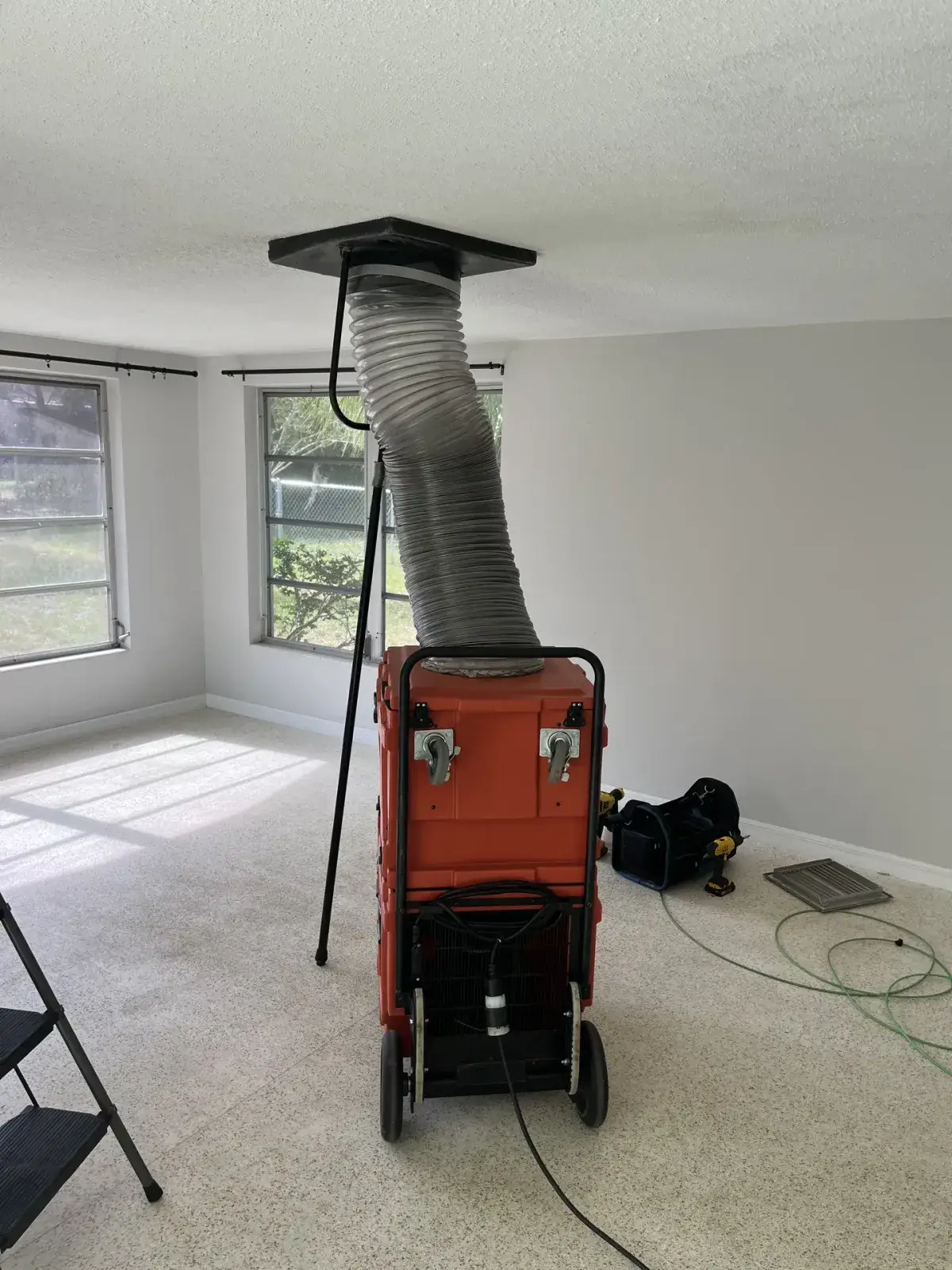A negative air machine hooked to a ceiling duct during a cleaning