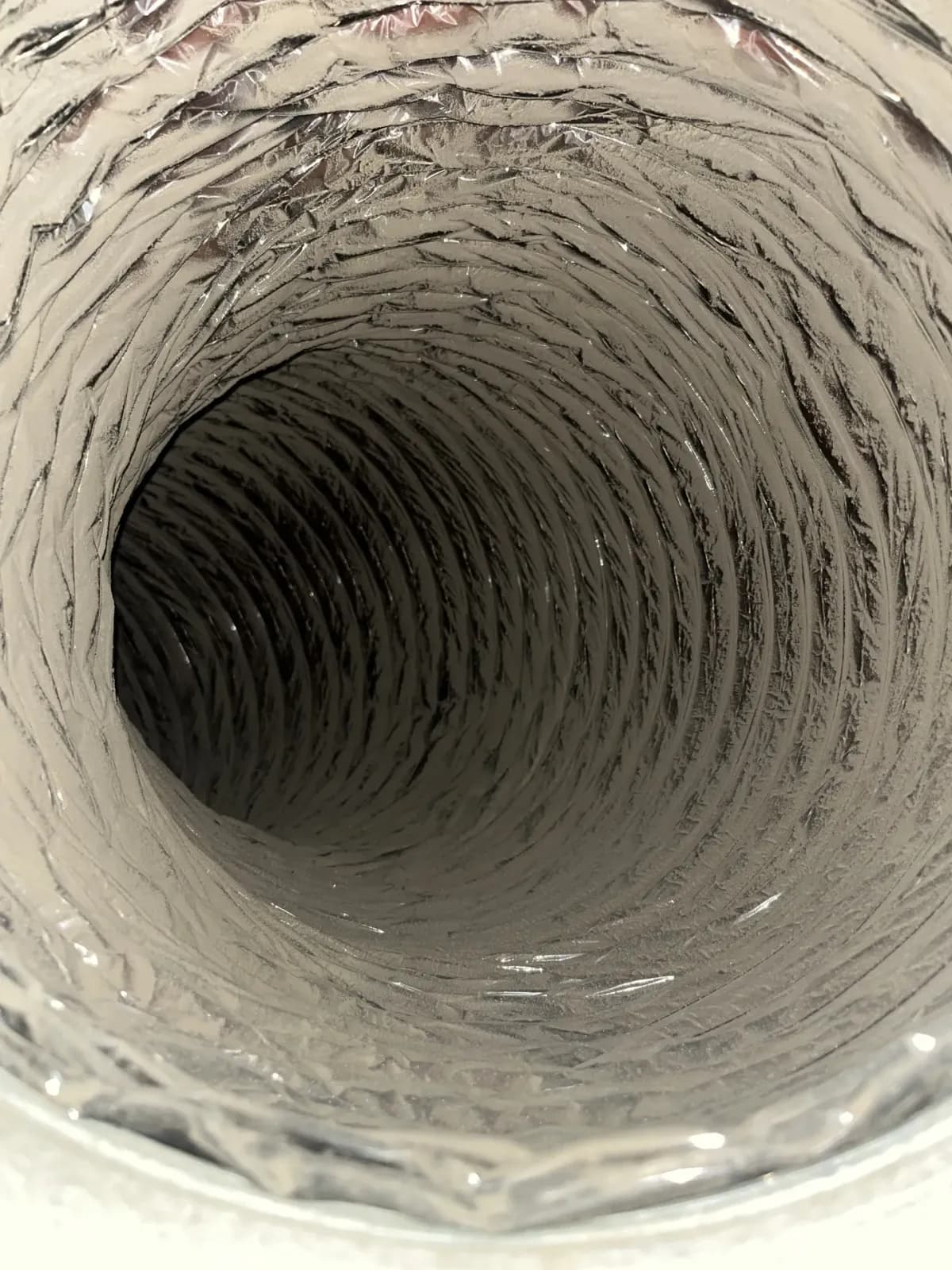 The ribbed inner liner of a flexible duct run, the surface compressed air cleans without touching