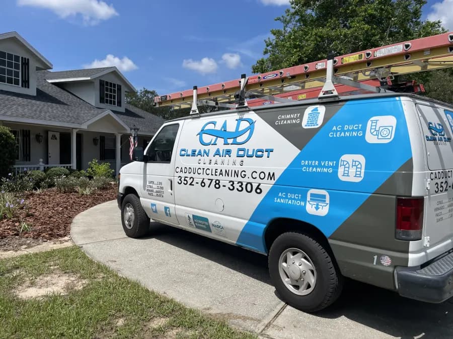 A Clean Air Duct Cleaning van with ladders on the roof rack, parked on the driveway of a Central Florida home