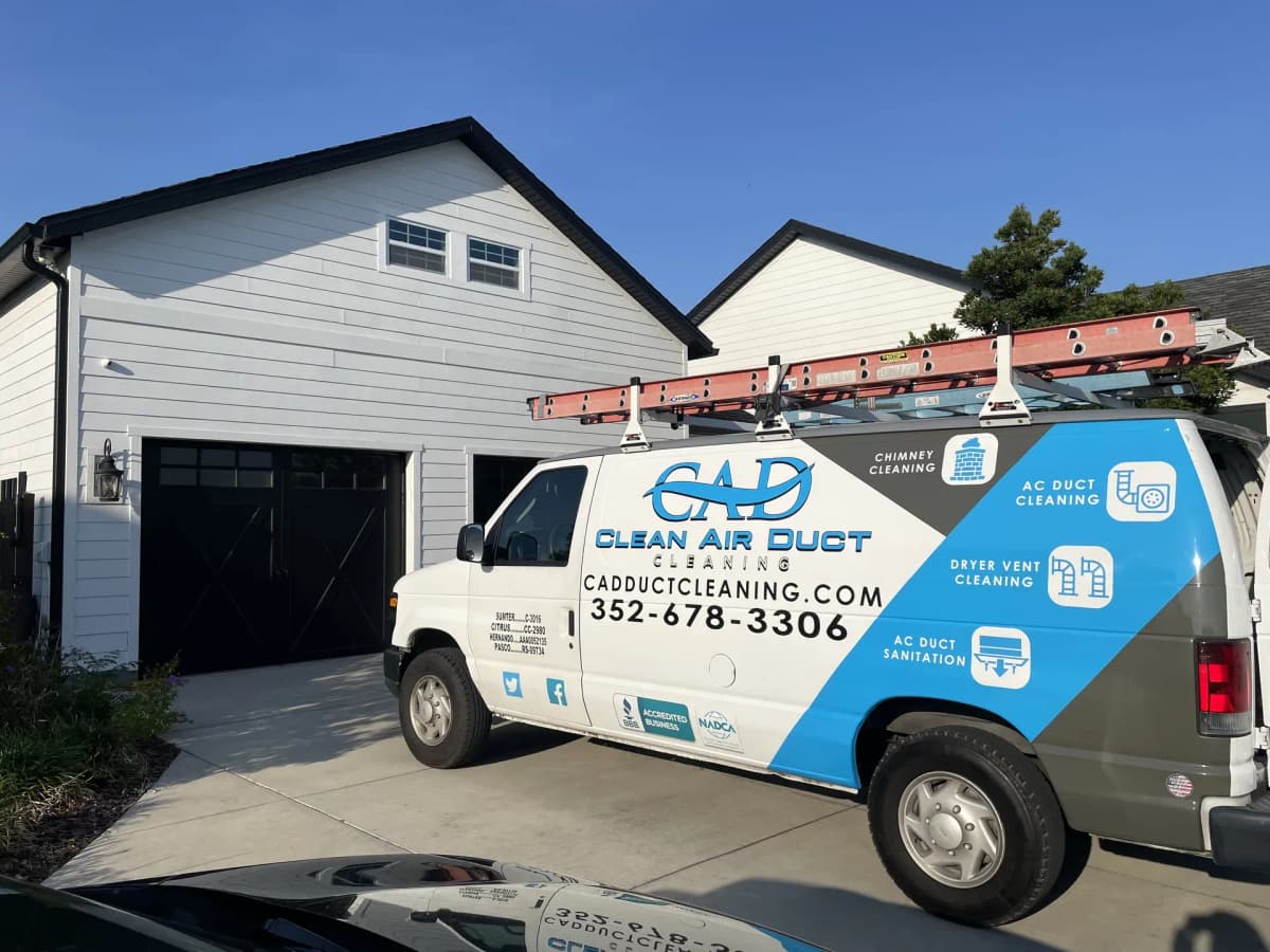 A Clean Air Duct Cleaning van on the driveway of a modern Florida home in evening light
