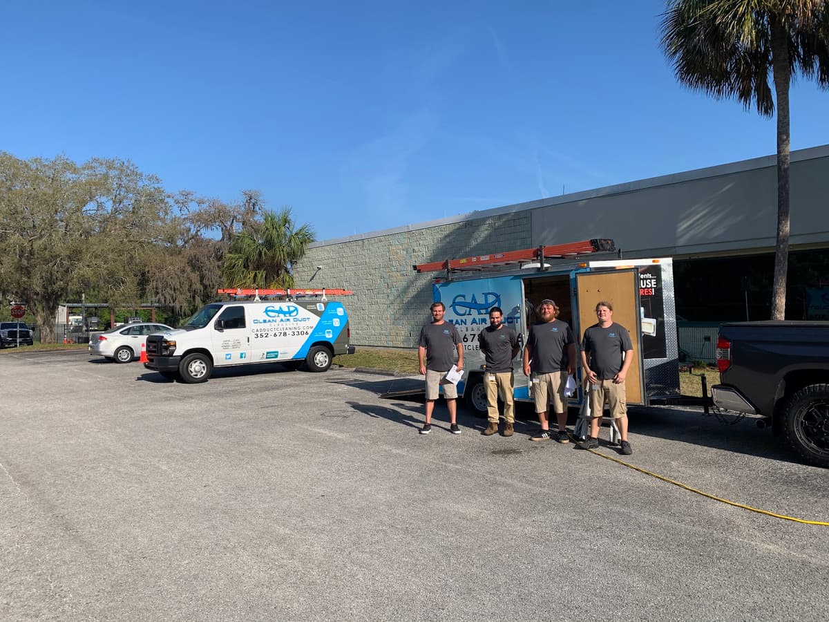 The Clean Air Duct Cleaning crew standing with their service vans outside the company workshop