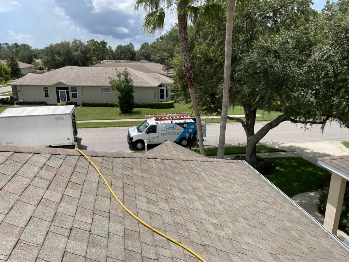 A Clean Air Duct Cleaning van on a driveway with an air line running to the house