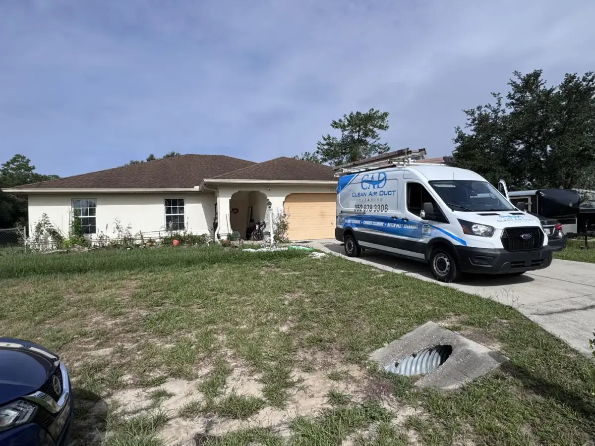 A Clean Air Duct Cleaning van parked at the curb outside a single-story block home