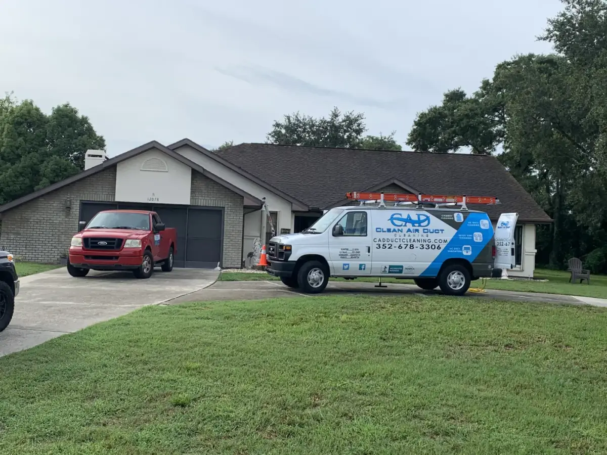 A Clean Air Duct Cleaning van parked outside a home with a carport