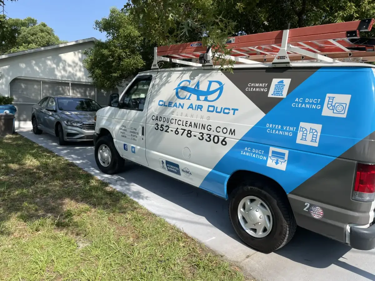 A Clean Air Duct Cleaning van parked beside a carport on a residential street