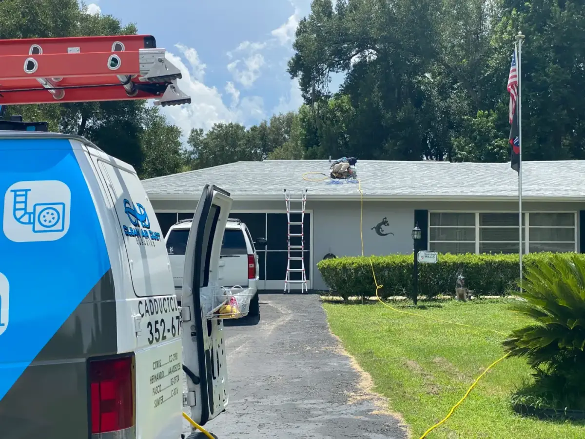 A Clean Air Duct Cleaning van in a driveway beside a US flag