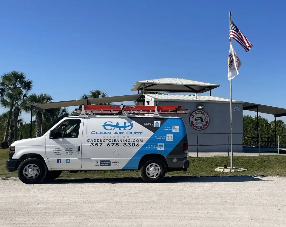 A Clean Air Duct Cleaning van parked outside a building with a US flag flying