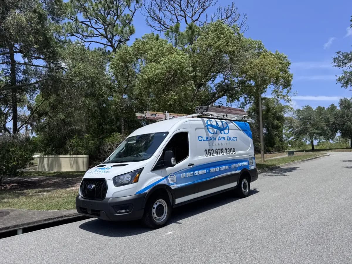 A Clean Air Duct Cleaning van parked on a road beside open water and trees