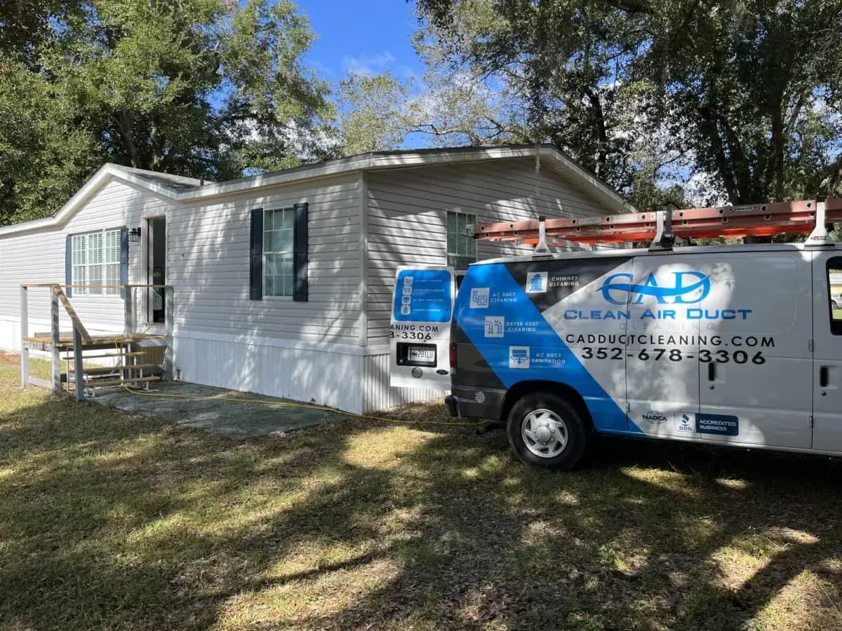 A Clean Air Duct Cleaning van parked beside a manufactured home under trees