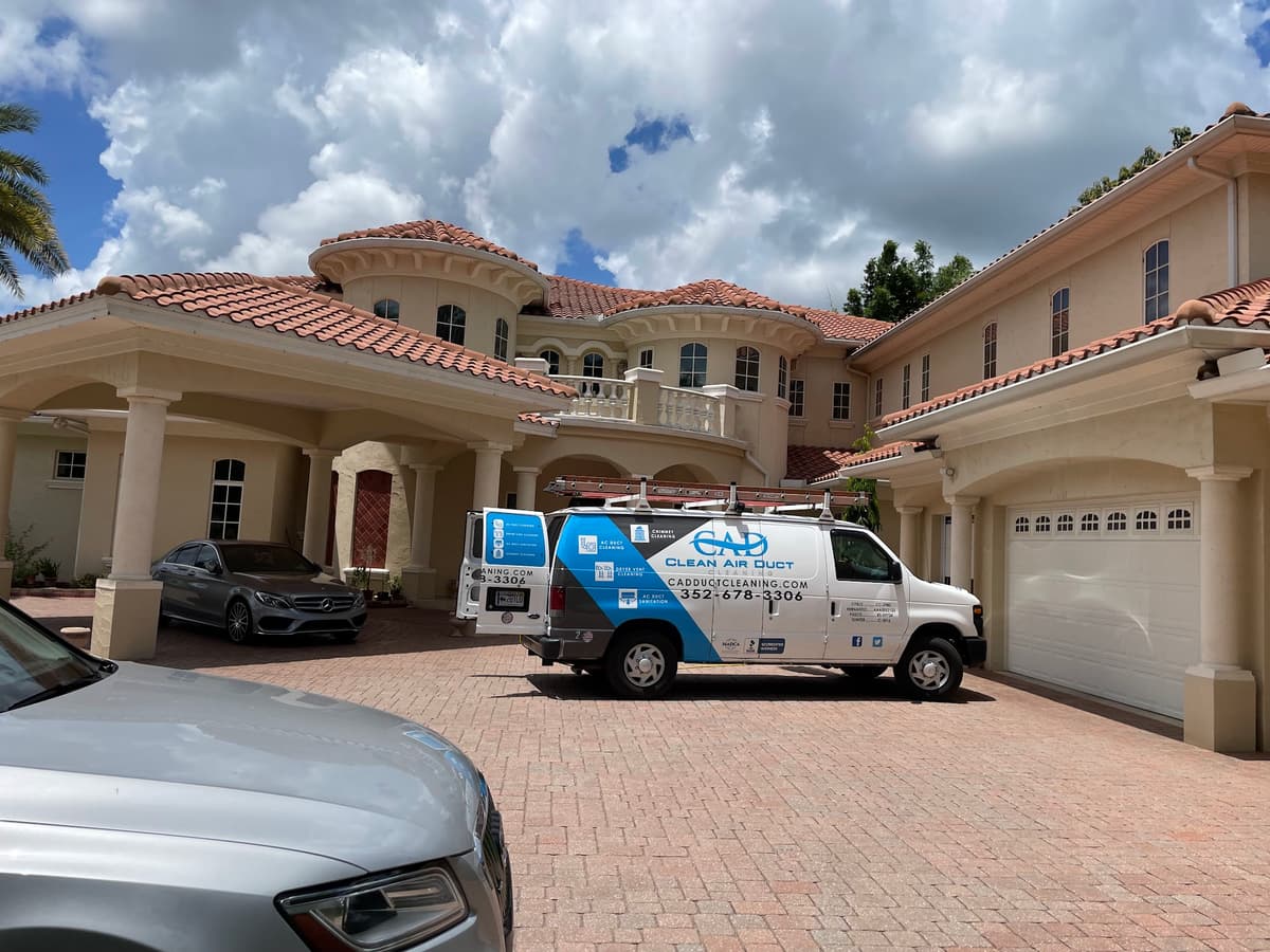 Clean Air Duct Cleaning van outside a large Mediterranean-style home in Central Florida