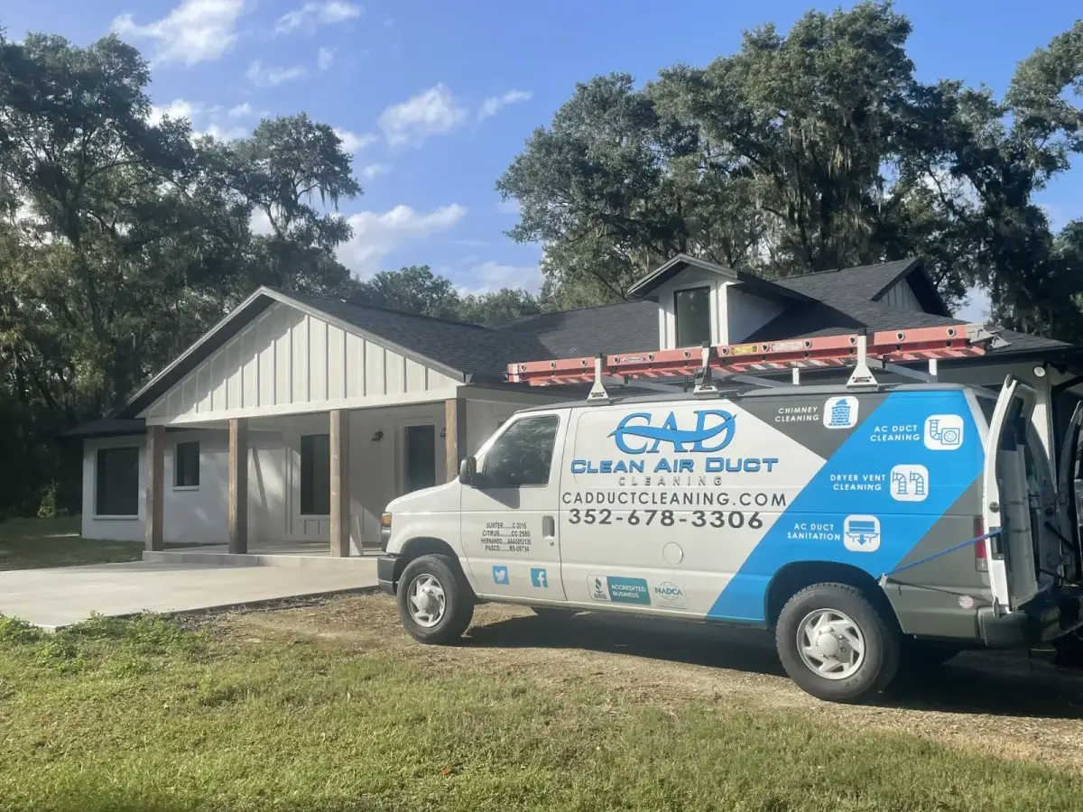 A Clean Air Duct Cleaning van outside a newer home with board-and-batten siding