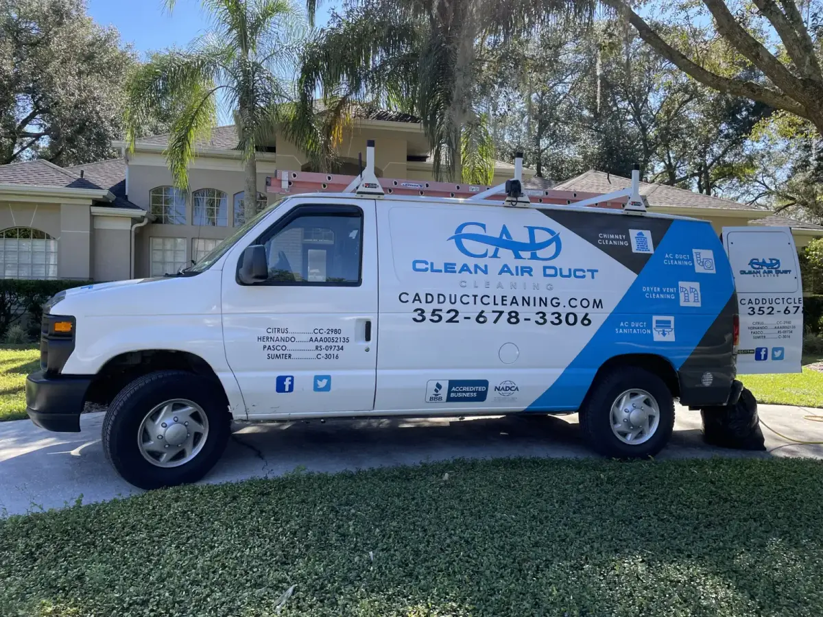 A Clean Air Duct Cleaning van parked outside a home shaded by mature oaks