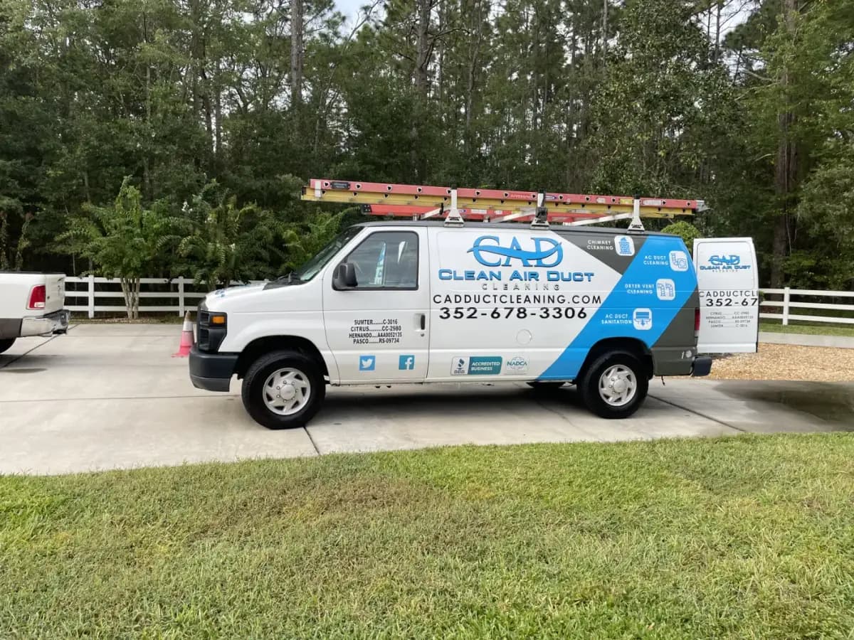 A Clean Air Duct Cleaning van parked at the edge of an open grassy lot