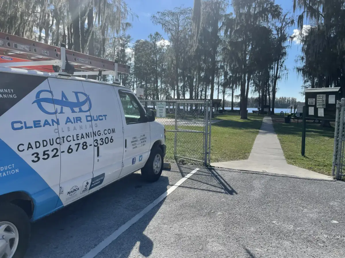 A Clean Air Duct Cleaning van parked beside a park with a lake behind it
