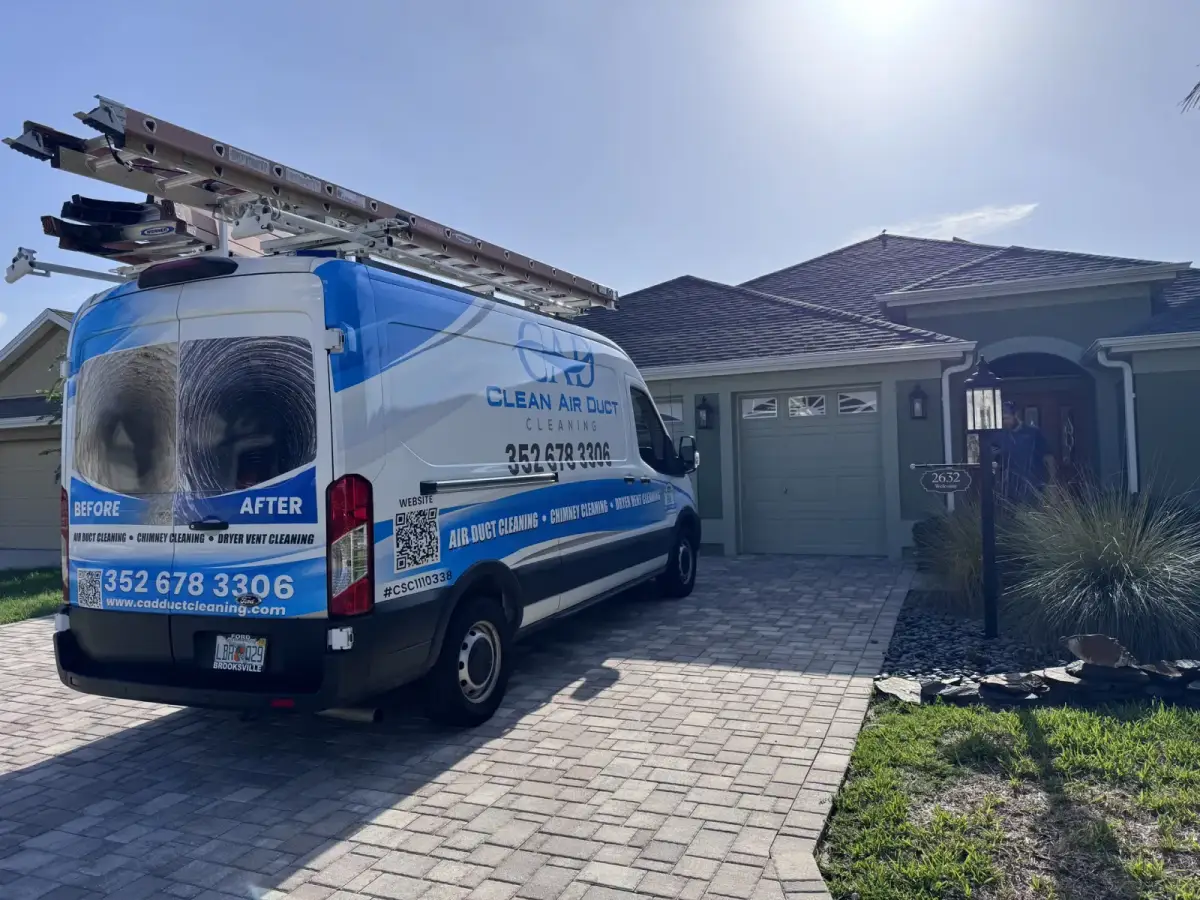 A Clean Air Duct Cleaning van parked on the paver driveway of a newer home