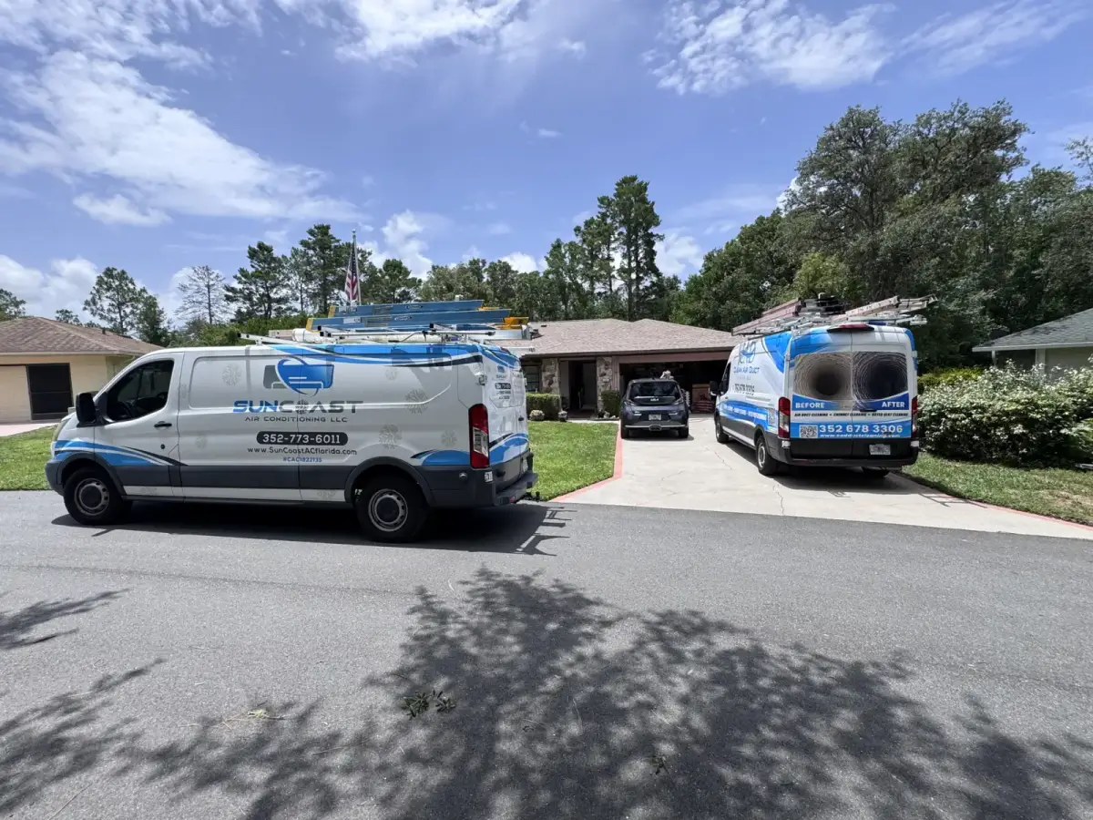 A Clean Air Duct Cleaning van parked under street trees outside a home