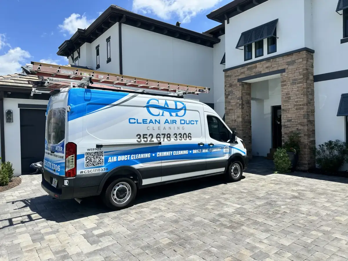 A Clean Air Duct Cleaning van on the driveway of a large home with a stone entry