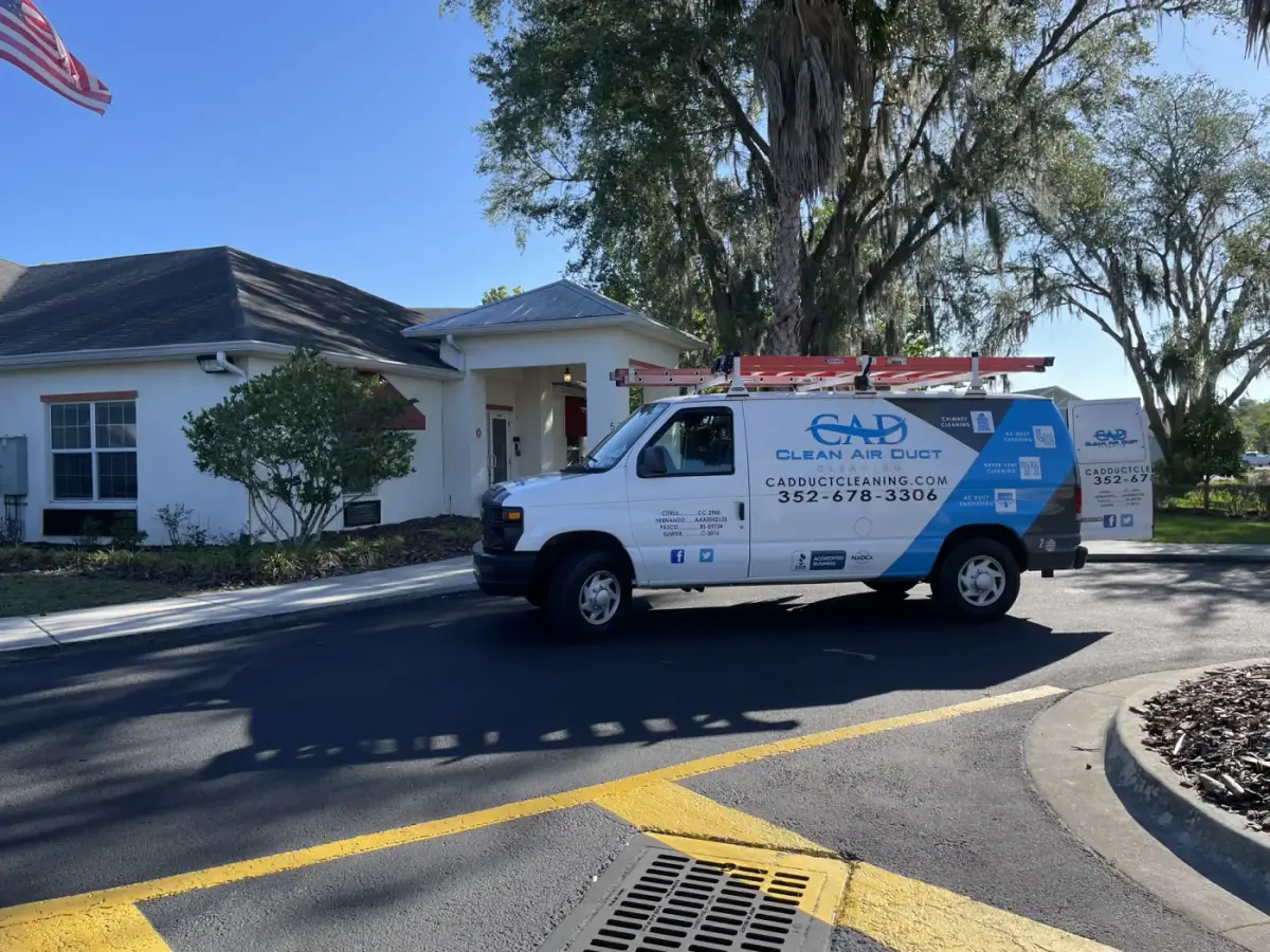 A Clean Air Duct Cleaning van outside a large white commercial building