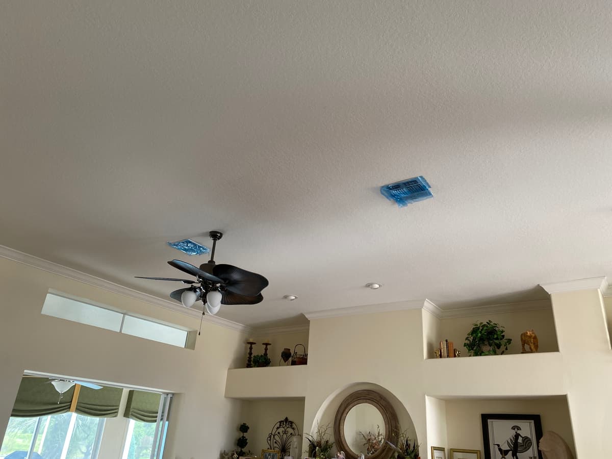 Covers taped over ceiling vents to contain dust during a residential duct cleaning