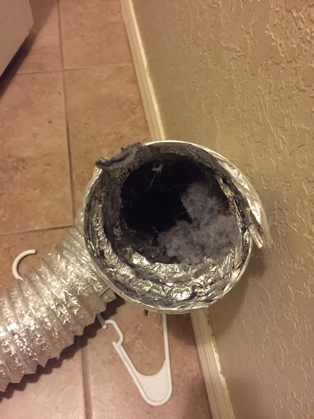 A dryer vent wall connection packed with lint behind a dryer