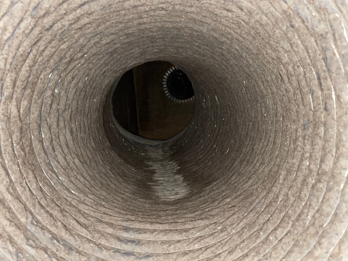 A duct with dust buildup and staining from past moisture before cleaning