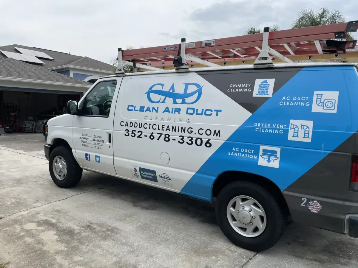 A Clean Air Duct Cleaning van on the driveway of a home with a tile roof