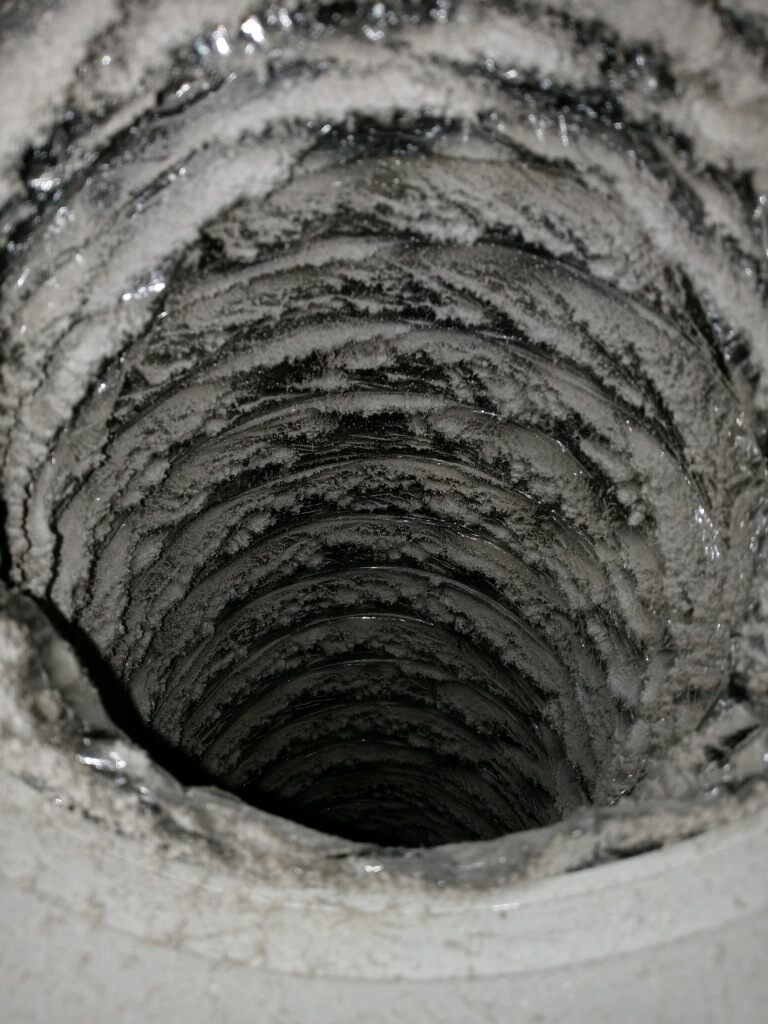 Inside a flexible air duct before cleaning, heavily coated with dust and debris